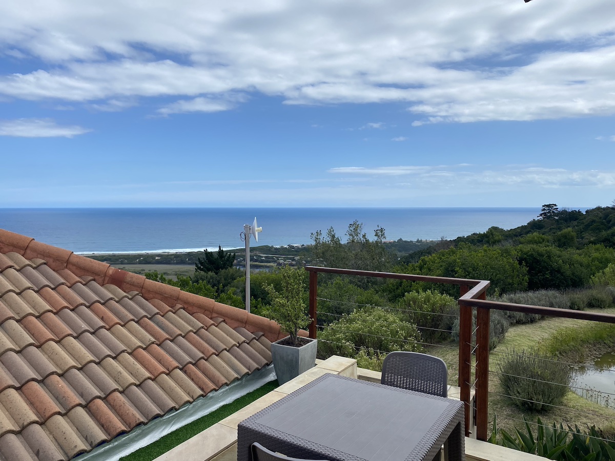 A stoep terrace and plunge pool with the sea beyond the rooftops