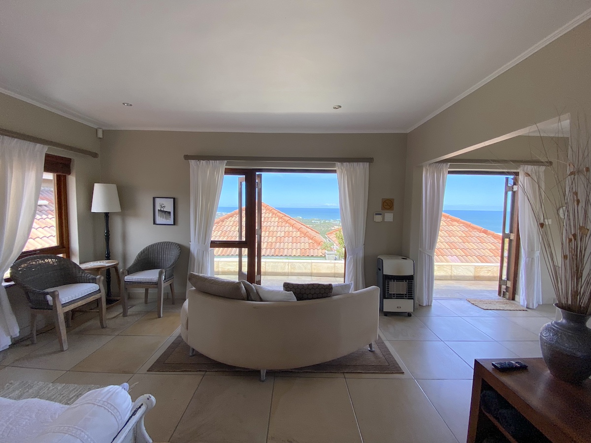 Lounge chairs and sofa at the windows, the sea beyond the roofs